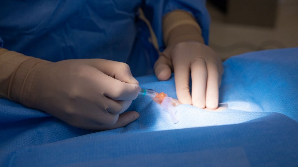 Detailaufnahme einer Infusion im Operationssaal mit Op-Licht-Spot auf Kanüle